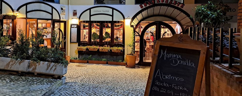 Arcadas de Paço de Arcos à noite, com o quadro de giz «Abrimos sexta-feira dia 22.09»