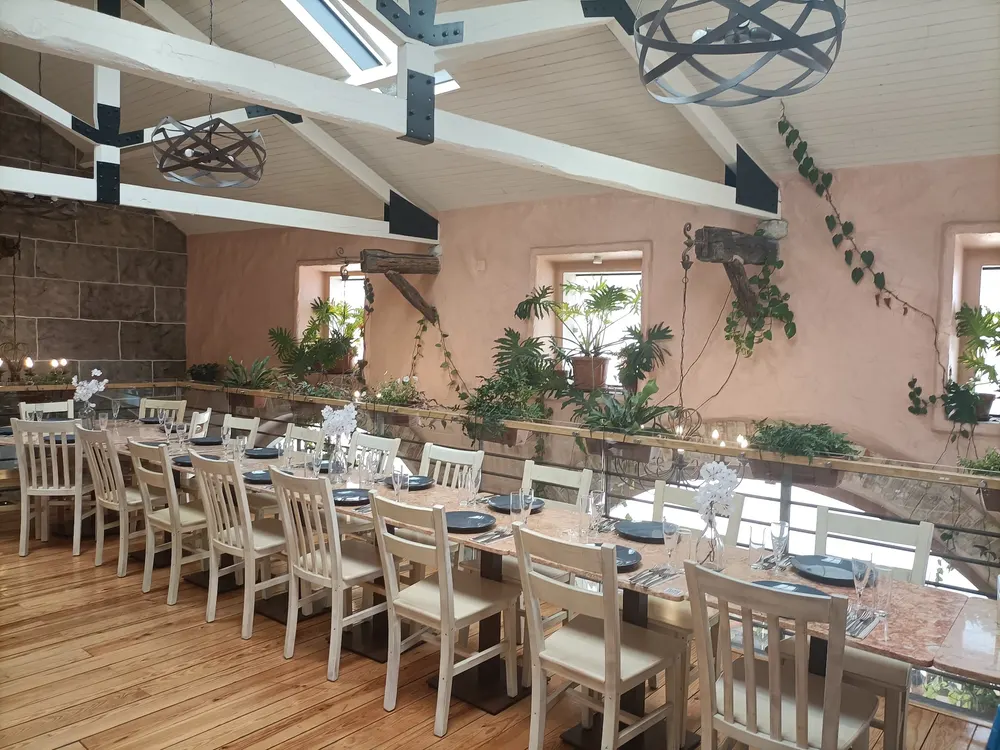 Mezanino de Massamá com uma mesa comprida, cadeiras brancas, paredes rosadas e plantas